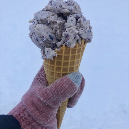 Blueberry ice cream in a waffle cone with a white snow background
