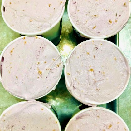 Six pints of of aronia berry ice cream with chunks of peaches and a silver background
